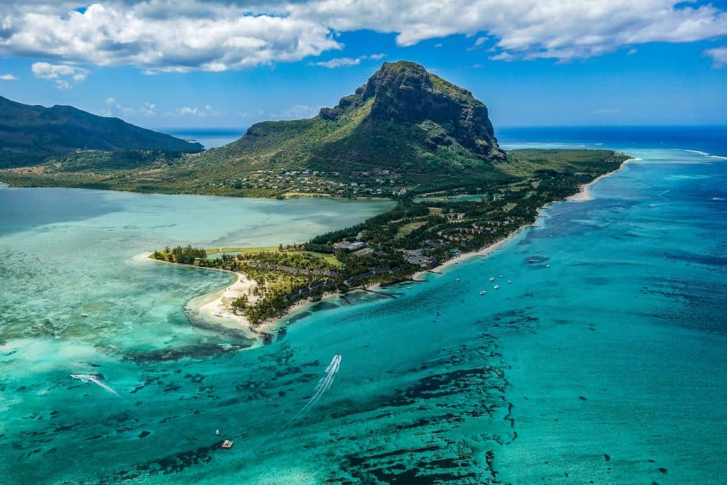 Aerial photo of the Paradis Beachcomber Golf Resort & Spa in Black River, Mauritius. The photo is heavenly, showing turquoise blue water, lush greenery and beautiful weather.