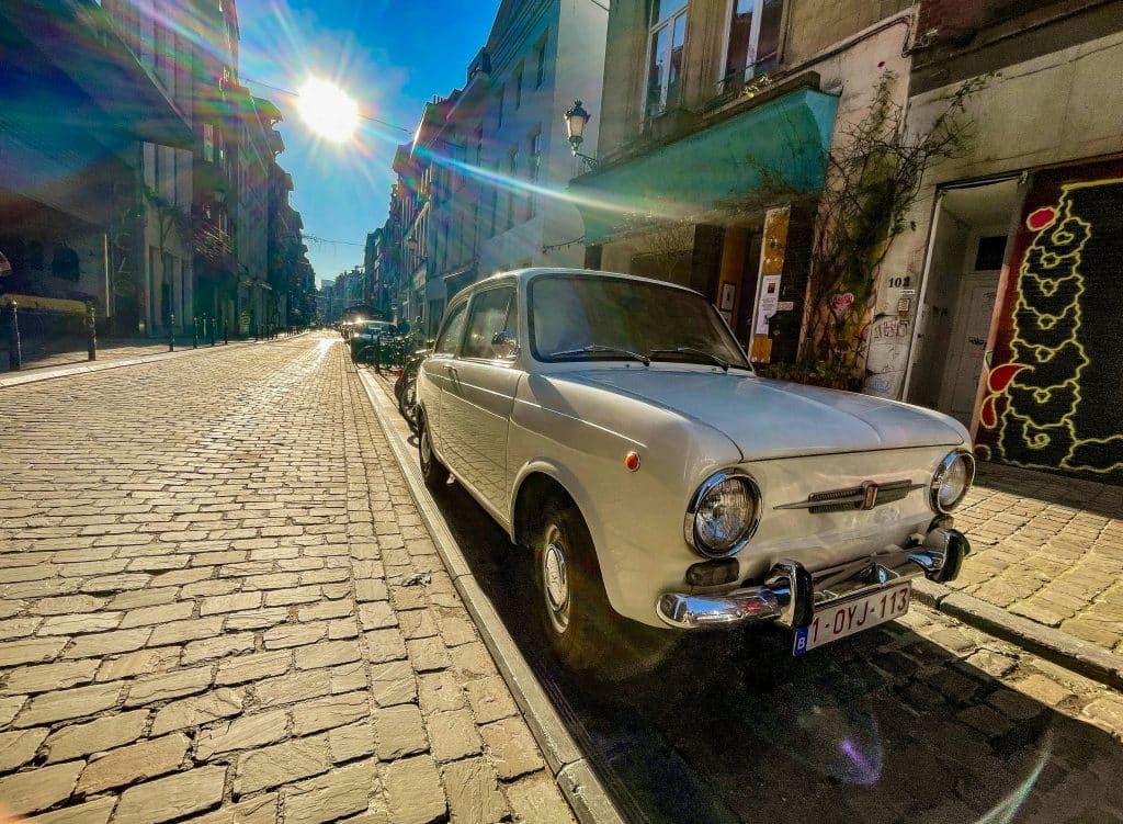 White vintage car parked on a cobbled street in Brussels, Belgium. The photo was taken from the front of the car.
