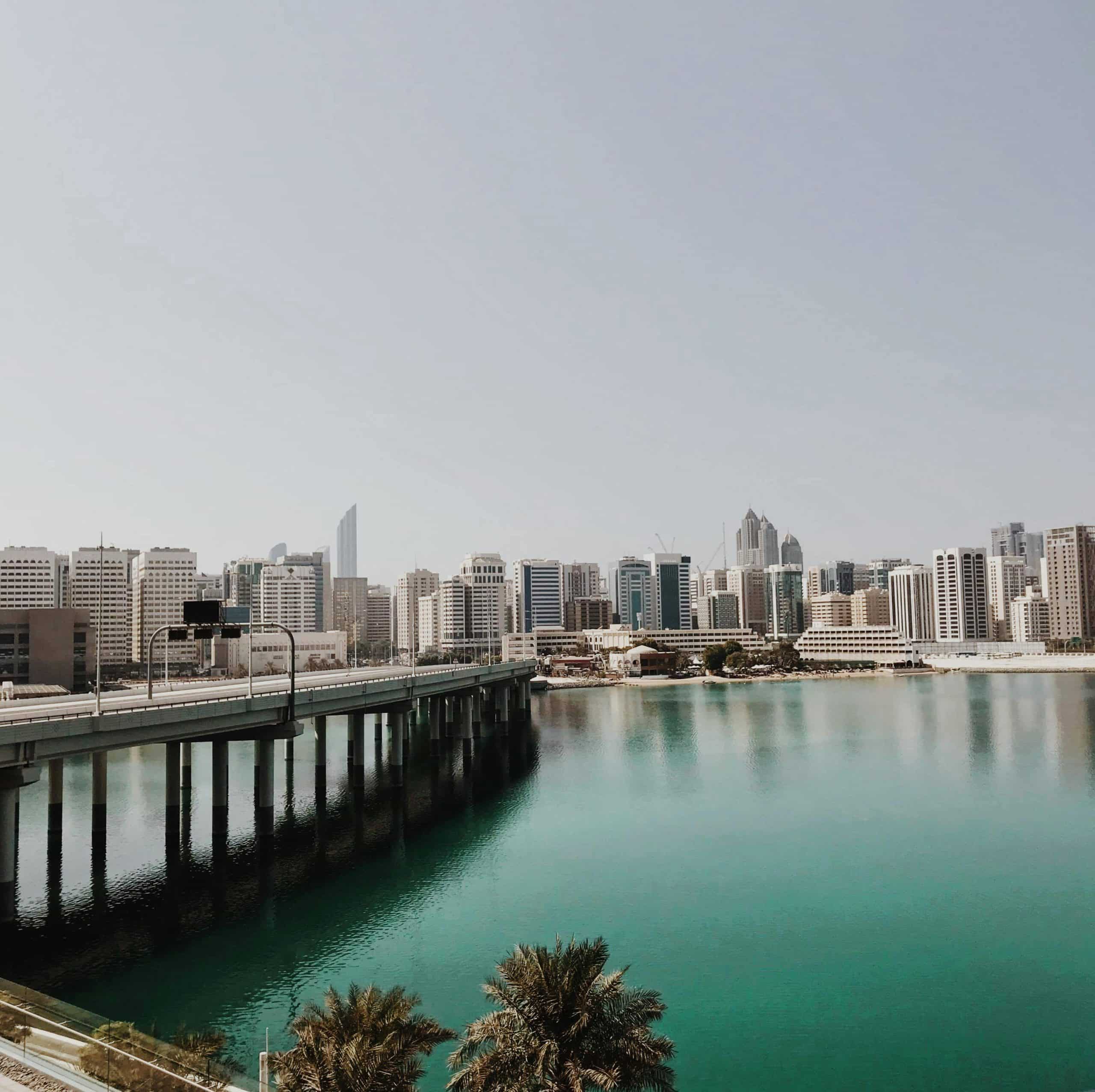 Photo of the blue sea along the Abu Dhabi coastline and tall buildings on the horizon.