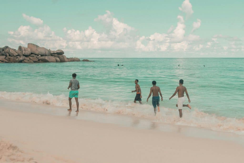 Young men are having fun on the paradise beach and running in the water.