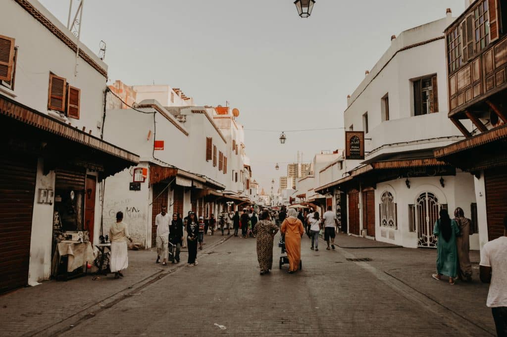 Photo of a street in a modest neighbourhood in Rabat, Morocco. Locals walking down the street.