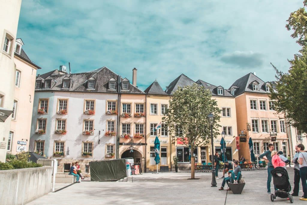 Photo taken on Place Guillaume in Luxembourg city centre on a spring day. A few people are walking around and chatting on the square.