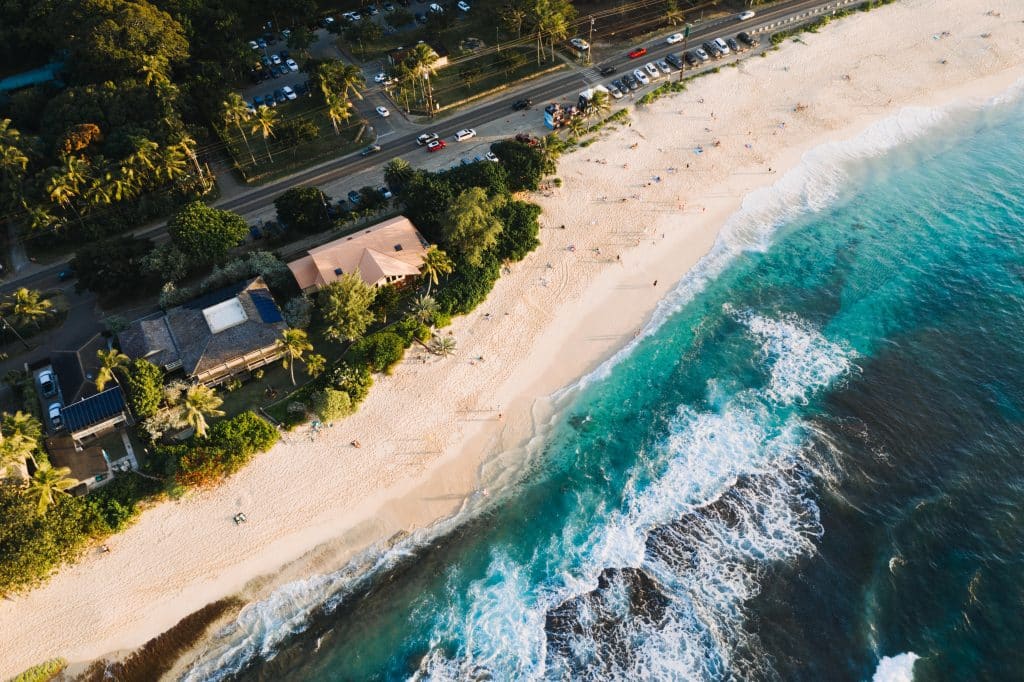 Houses and road by the sea in the Seychelles, aerial view. People relaxing on the sandy beach.