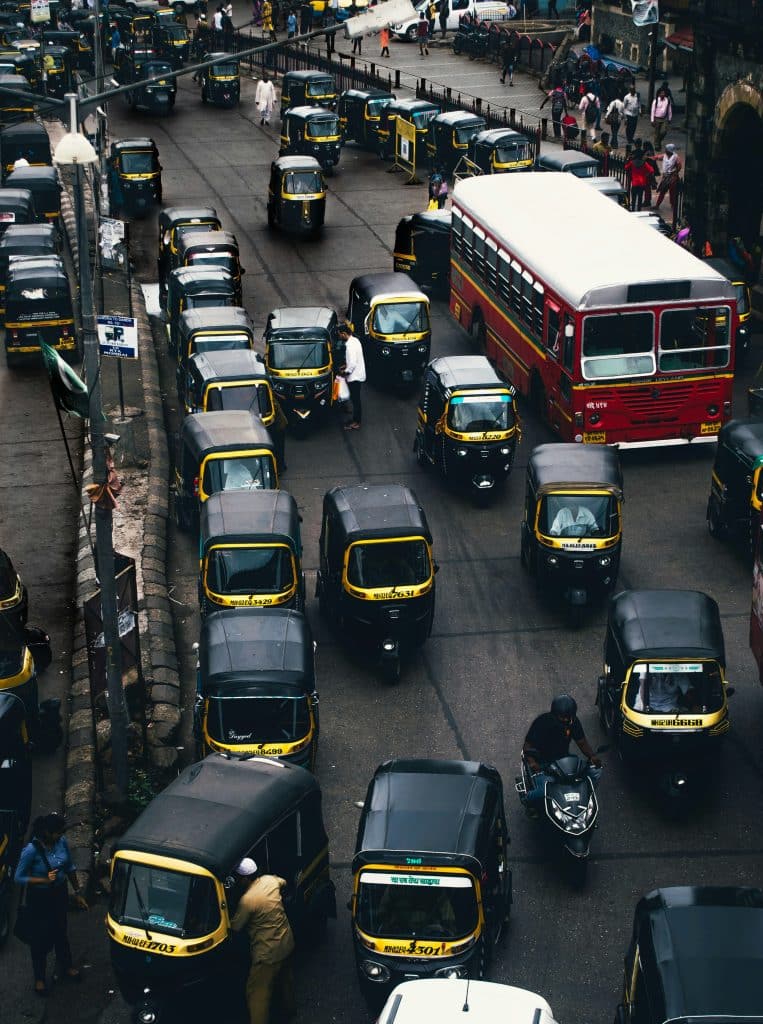 A swarm of black and yellow taxis in the city of Mumbai, India, on a day with very heavy traffic. The photo is generally very dark.