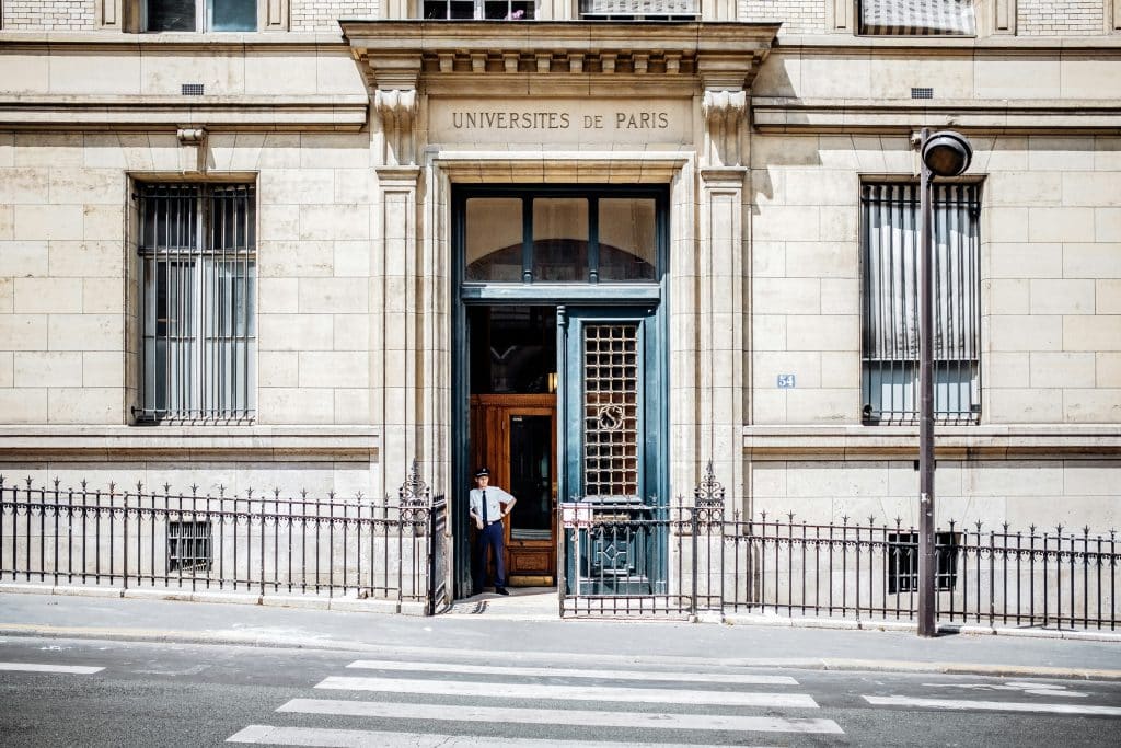 Facade of the Sorbonne University in Paris. A security guard stands at the door.